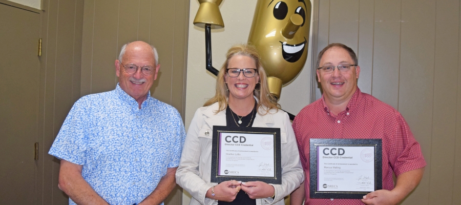 Mel Coleman presents Heather Loftis and Marc Walling certificates. 
